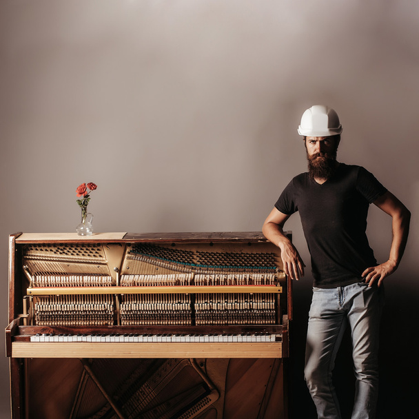 bearded man in helmet near wood piano - Photo, image