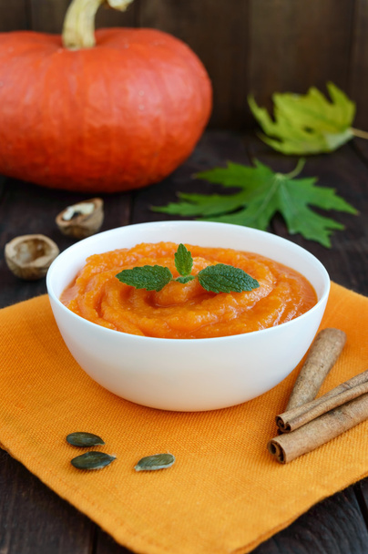 Organic pumpkin puree (soup) in a white bowl on dark wooden background. - Photo, Image