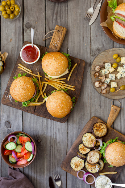 Different burgers with snacks on wooden table - Fotografie, Obrázek