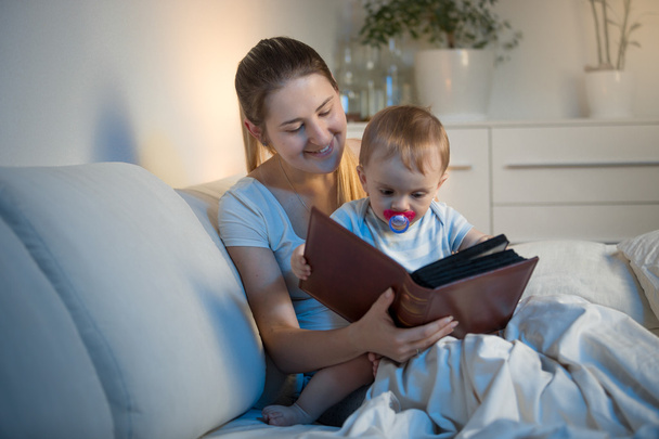 Retrato da bela mãe lendo livro para seu bebê antes de goi
 - Foto, Imagem