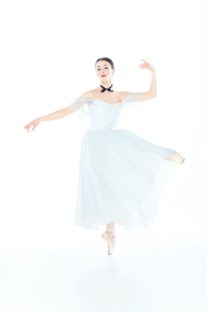 Ballerina in white dress posing on pointe shoes, studio background. - Foto, imagen