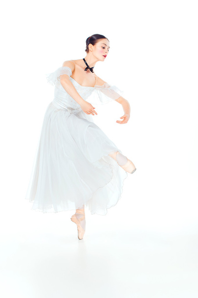 Ballerina in white dress posing on pointe shoes, studio background. - Foto, afbeelding