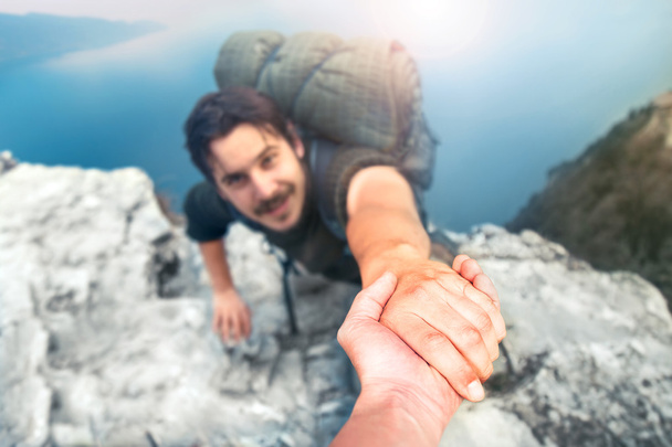 seikkailijat auttavat toisiaan kiivetä vuorelle
 - Valokuva, kuva