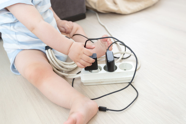 Closeup of baby boy pulling out cables from electrical extension - Фото, зображення