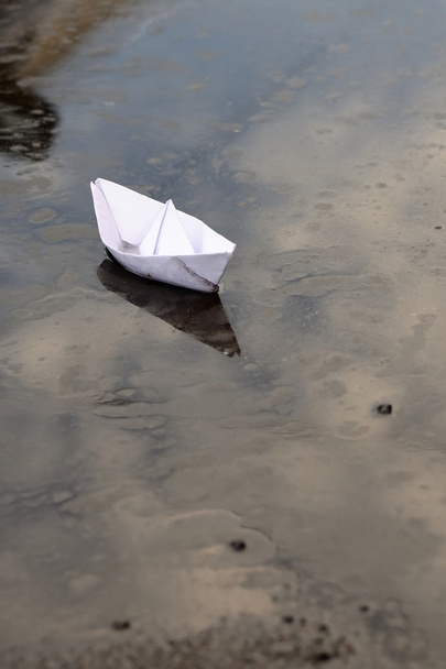 Βάρκα που κατασκευάζεται από λευκό χαρτί σε μια λακκούβα του βρώμικου νερού - Φωτογραφία, εικόνα