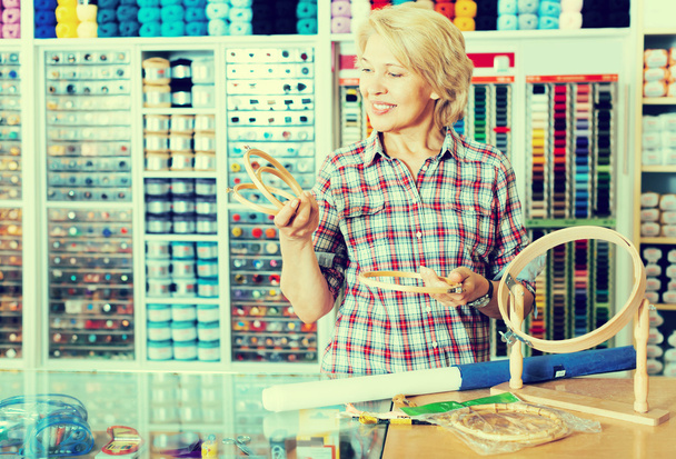 зріла жінка за лічильником в швейному магазині
 - Фото, зображення