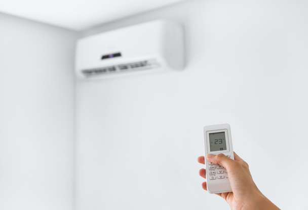 Remote control for air conditioner on a white wall. - 写真・画像