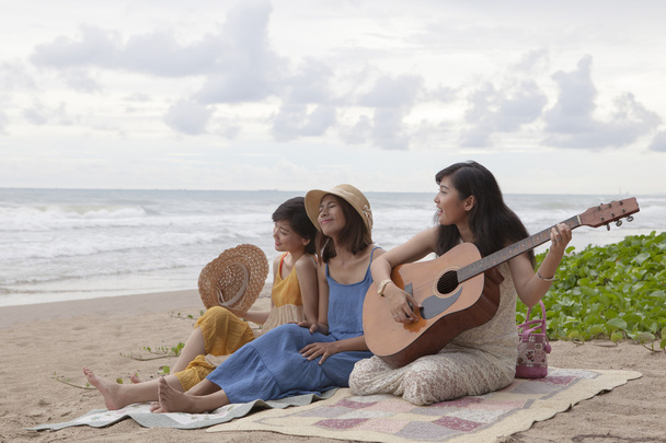 jonge Aziatische vrouw vriend gitaarspelen op zee strand geluk e - Foto, afbeelding