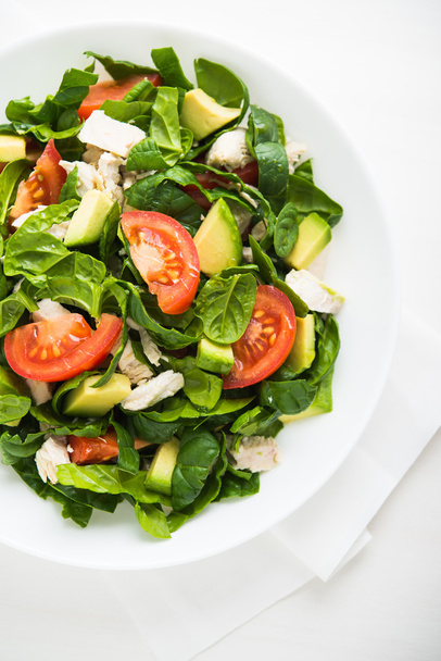 frischer Salat mit Hühnchen, Tomaten, Spinat und Avocado auf weißem Holzhintergrund. - Foto, Bild
