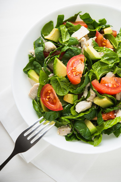frischer Salat mit Hühnchen, Tomaten, Spinat und Avocado auf weißem Holzhintergrund. - Foto, Bild