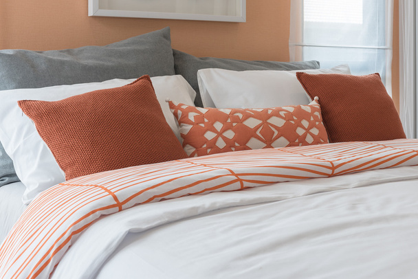 Orange color tone pillows set on bed in modern bedroom
  - Фото, изображение