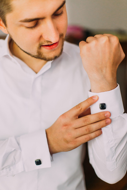 Elegant young fashion caucasian man in white shirt fixing his cufflinks - Фото, изображение