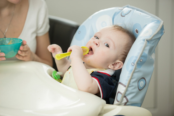 Μωρό παίζει με κουτάλι, ενώ το φαγητό - Φωτογραφία, εικόνα