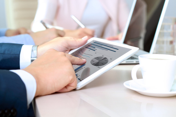 Geschäftskollegen arbeiten zusammen und analysieren Finanzzahlen auf einem digitalen Tablet - Foto, Bild
