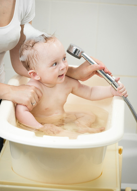 Cheerful baby boy playing with shower head in bath - Photo, Image