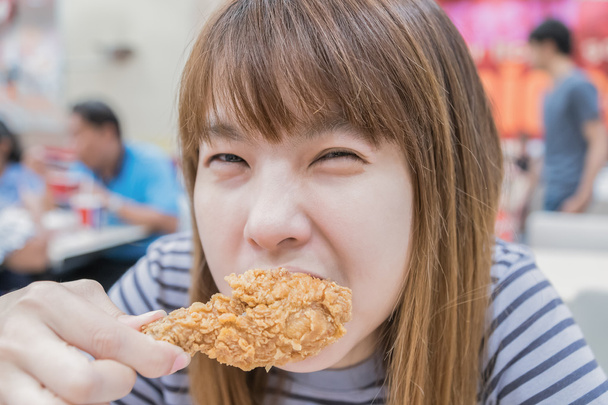 Joven mujer feliz sosteniendo y comiendo papas fritas pollo
 - Foto, Imagen