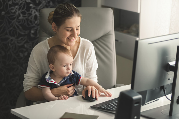 Usmívající se žena pracující v počítači se svým malým synem baby - Fotografie, Obrázek