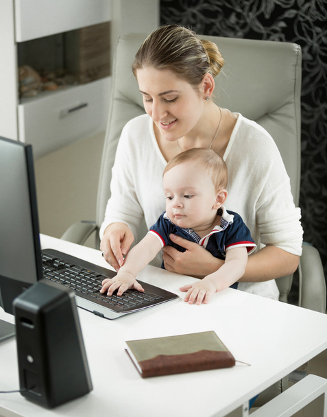 Портрет женщины, которая учит своего маленького сына пользоваться компьютером
 - Фото, изображение