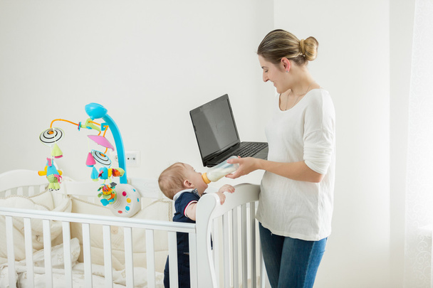 Young woman with baby working at home on laptop - Foto, immagini
