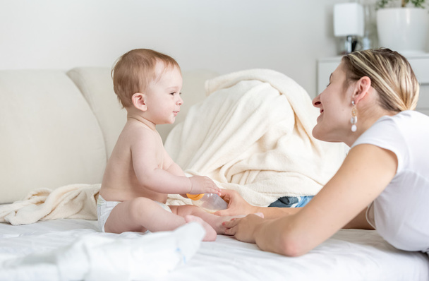 Onnellinen nuori äiti puhuu hänen 9 kuukautta vanha vauva istuu
 - Valokuva, kuva