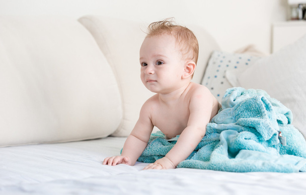 Baby boy after shower covered in blue blanket on sofa at living  - Foto, afbeelding