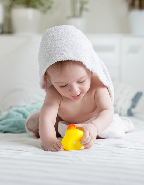 Portrait of happy baby in hooded towel playing with yellow rubbe - Foto, immagini