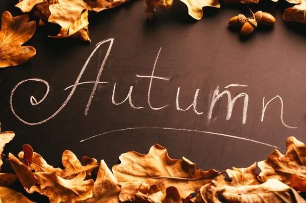 Żółte liście i jesienią napis na tablicy - Zdjęcie, obraz