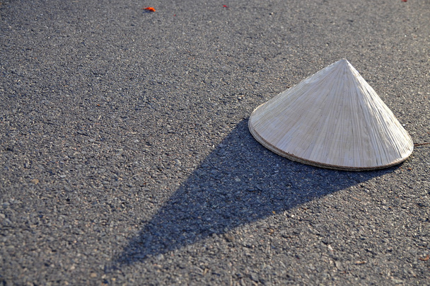 Chapéu de folha tradicional vietnamita com sombra no surf de estrada quente
 - Foto, Imagem