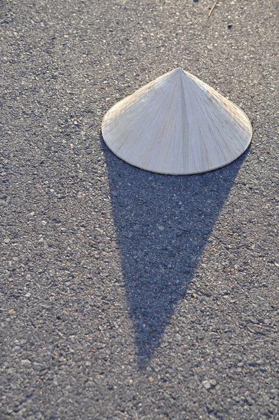 Chapéu de folha tradicional vietnamita com sombra no surf de estrada quente
 - Foto, Imagem