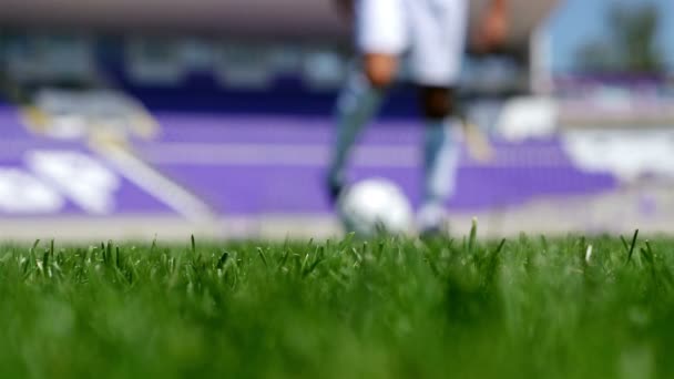 Visão de baixo ângulo de um futebolista liderando a bola em um campo de futebol
 - Filmagem, Vídeo