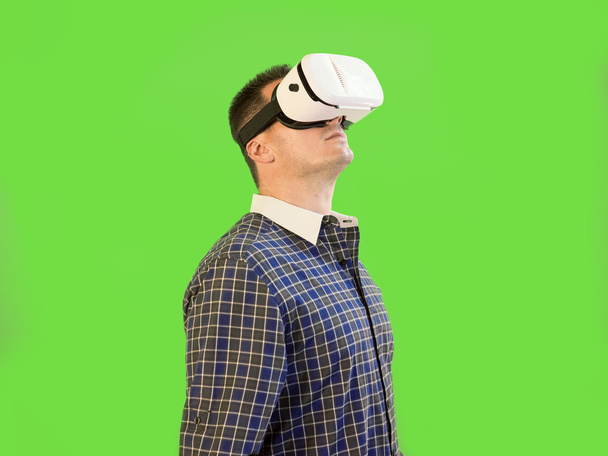 Chlap hledá ve virtuální realitě na sobě 360 Googles zelenou obrazovku - Fotografie, Obrázek