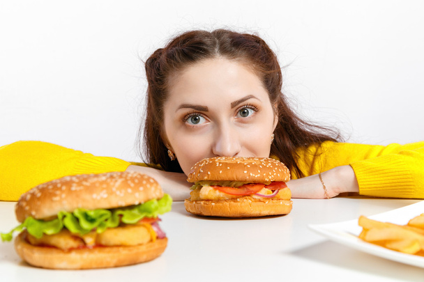 Girl bites off a huge hamburger. Unhealthy diets.  - Fotó, kép