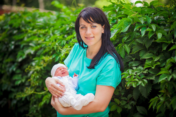 Mother holding newborn baby in a park - Photo, Image