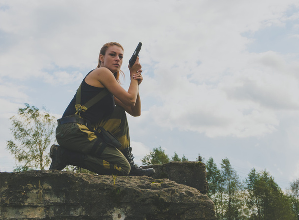 threat beautiful girl in uniform with a gun - Фото, изображение