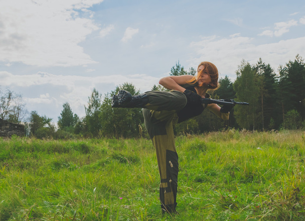 dangerous girl in the form of soldiers with weapons ready for a kick - Foto, afbeelding