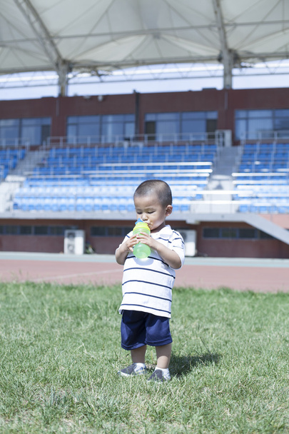 Roztomilé čínské baby boy pitné vody na stadionu - Fotografie, Obrázek
