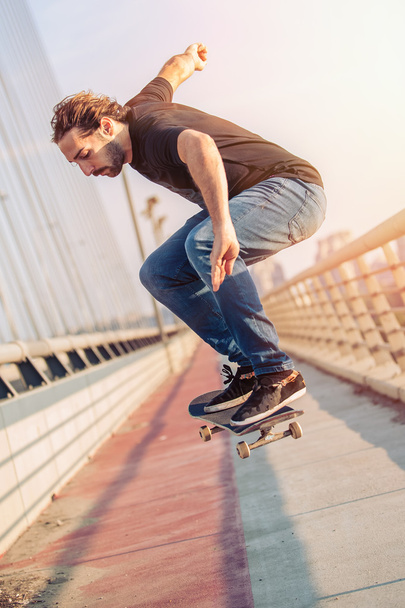 Skateboarder skates and doing jumps over a city bridge - Foto, Imagem