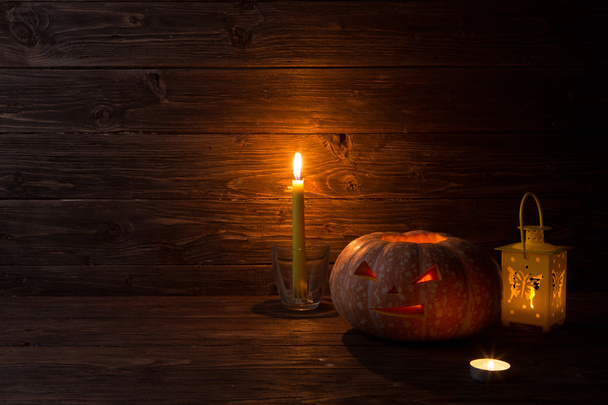 Halloween carved pumpkin and candle on wooden background - Foto, afbeelding