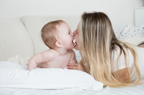 Πορτρέτο του χαρούμενο μωρό με τη μητέρα που βρίσκεται στο μεγάλο λευκό μαξιλάρι - Φωτογραφία, εικόνα