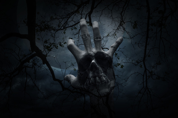 Hand blend with human skull over dead tree, Halloween concept - Фото, изображение