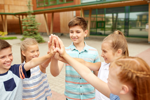 grupo de niños haciendo high five en el patio de la escuela
 - Foto, imagen