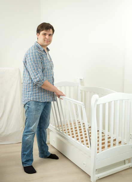 Padre expectante armando cama para su futuro bebé
 - Foto, Imagen