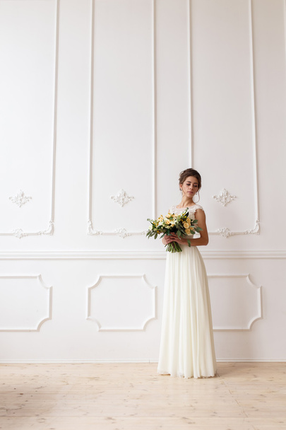 bride holding wedding boho bouquet on a background of a white wall relief - Фото, зображення