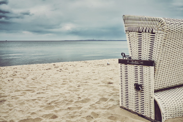 Ретро тоноване плетене крісло з капюшоном на порожньому пляжі
. - Фото, зображення