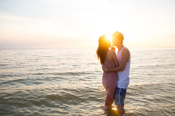 Jeune couple étreignant au coucher du soleil dans la mer
 - Photo, image