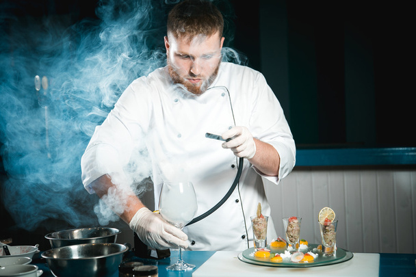 Chef barbu joyeux cuisiner pendant la cuisson des repas dans la cuisine
 - Photo, image