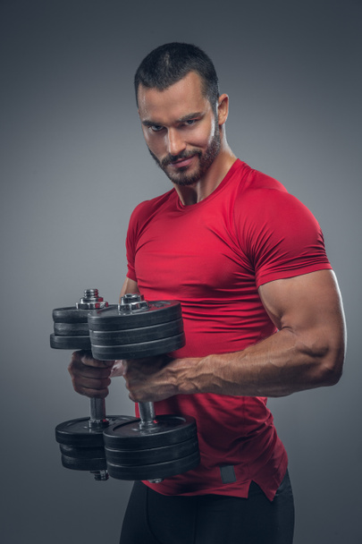 Male in a red t shirt holds dumbbells - Photo, Image