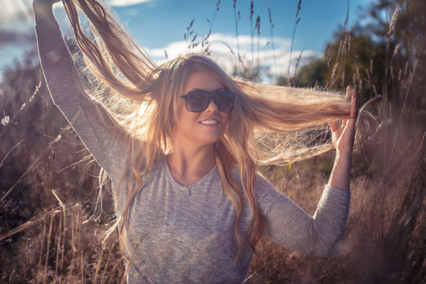 Blond žena v sluneční brýle v poli. - Fotografie, Obrázek