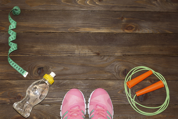 Sport shoes, skipping rope and water bottle on wooden background. Sport, diet and healthy lifestyle concept. Clothing and sports accessories for fitness. The view from the top. The place to advertise. - Photo, Image