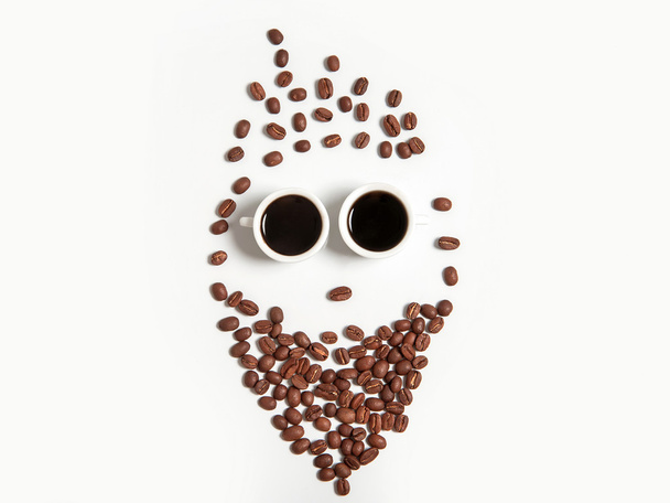 Veselý obličej z kávových bobů v šálcích izolovaných na bílém - Fotografie, Obrázek